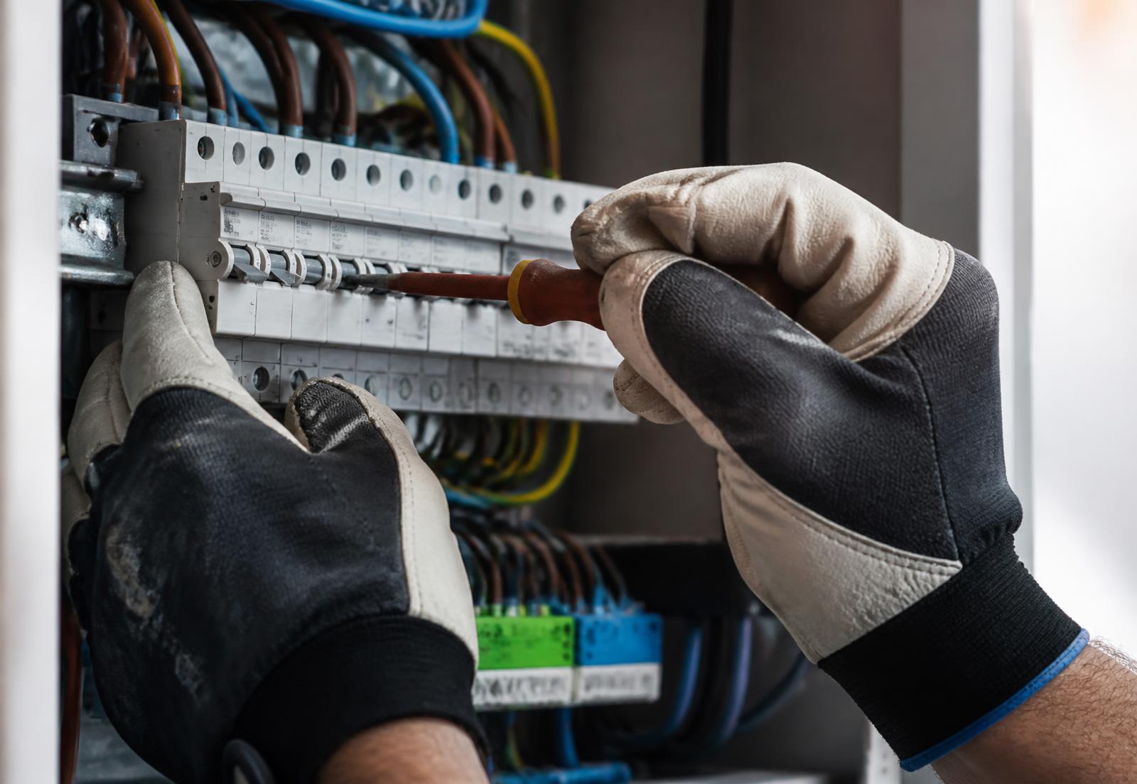 Mãos de eletricista trabalhando em um quadro de disjuntores